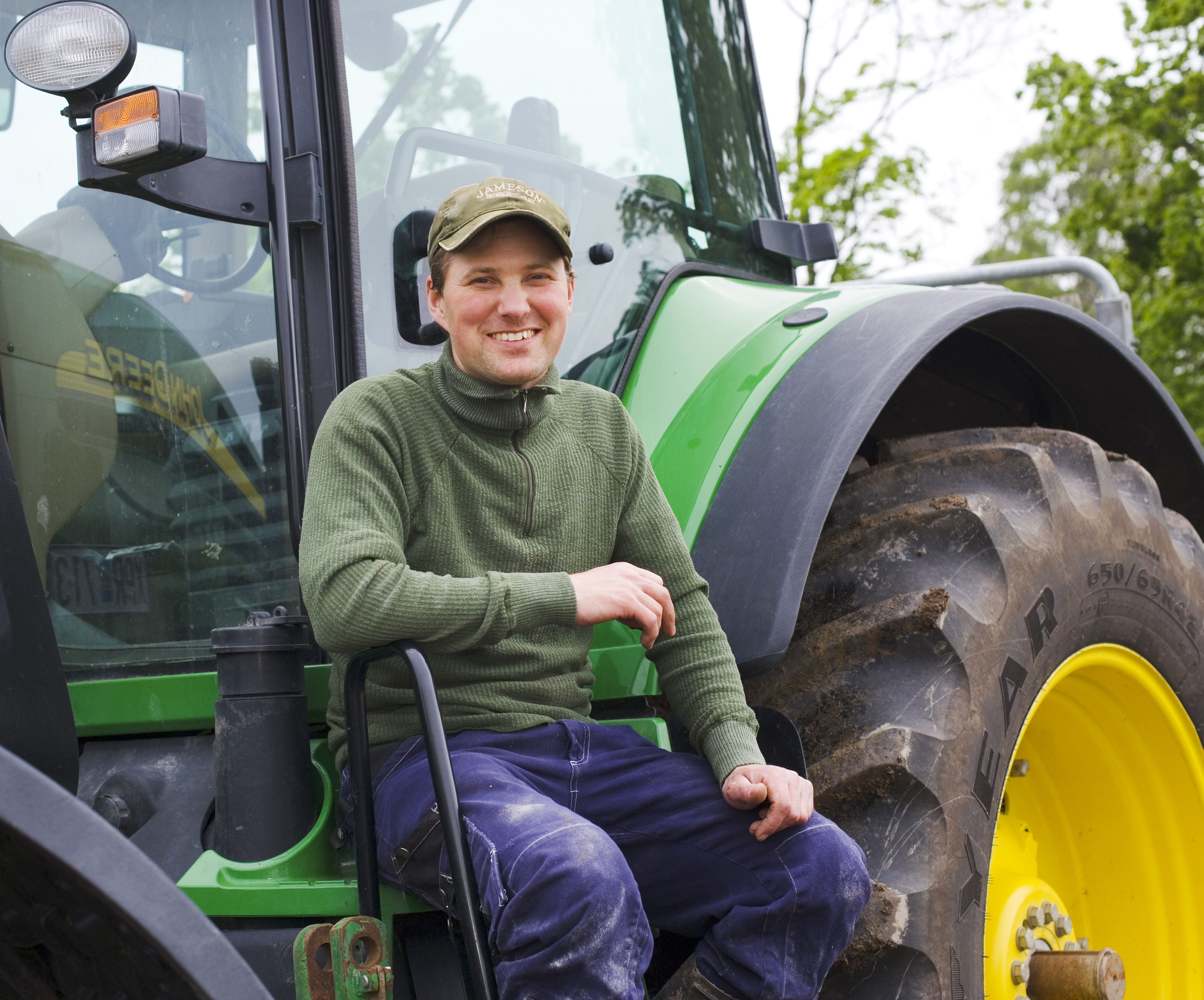 En leende bonde sitter vid sin traktor