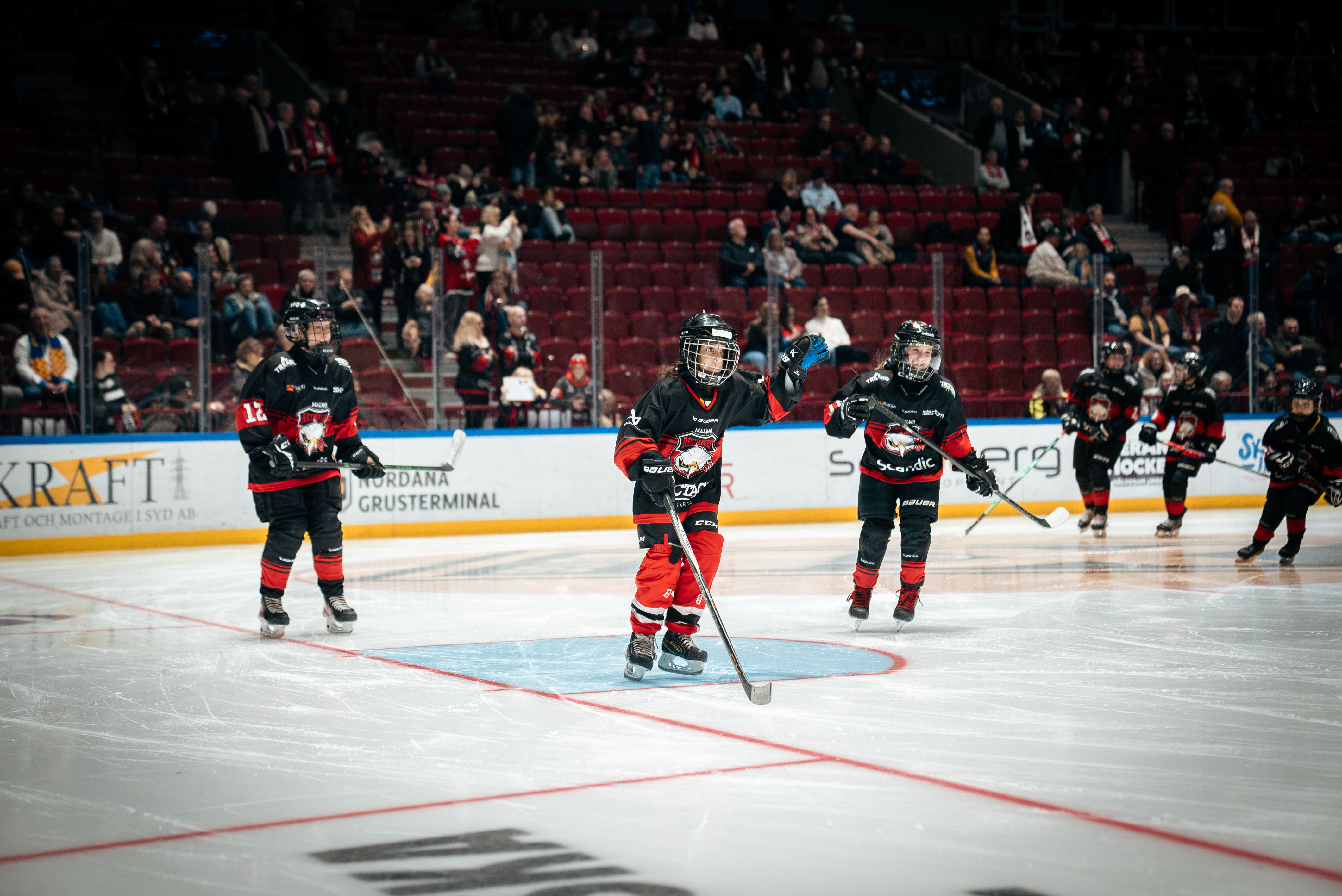 Barn spelar hockey i en hockeyarena.